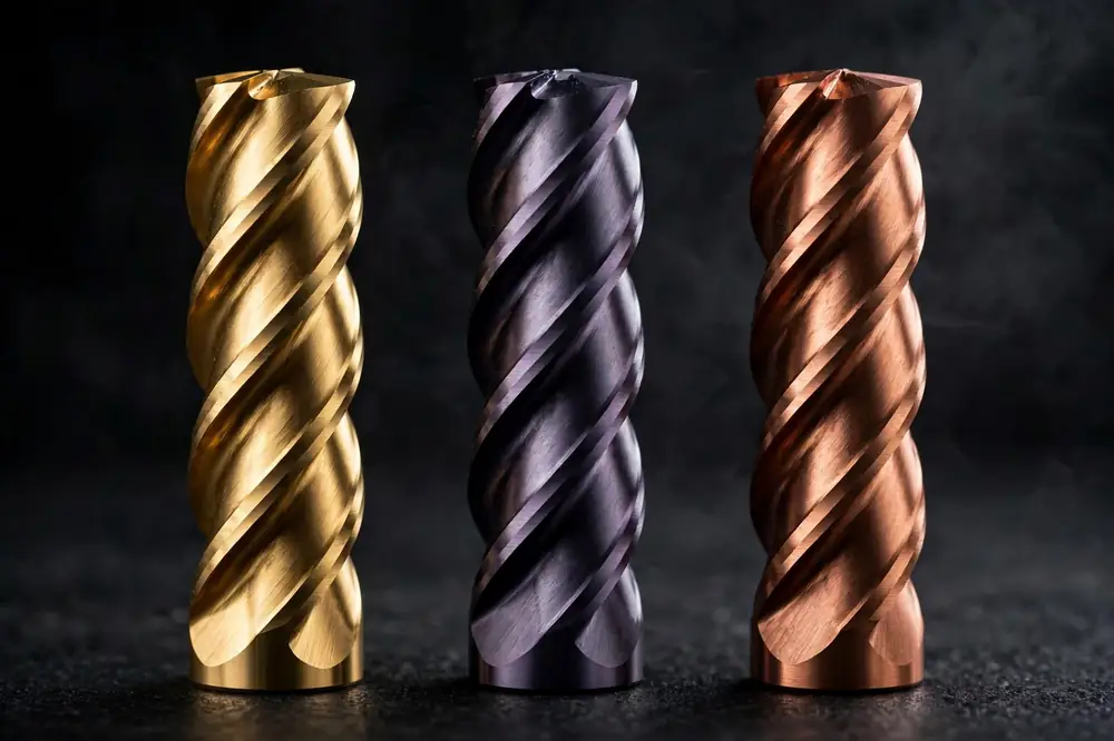 Three carbide end mills showing different PVD coatings: gold titanium nitride, violet-gray titanium aluminum nitride, and bronze finishes