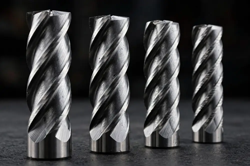 Four carbide end mills standing in a row showing two, three, four, and five flutes from left to right