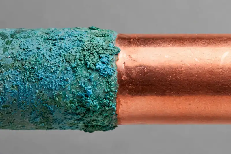 Copper pipe half covered in green patina, half cleaned bright